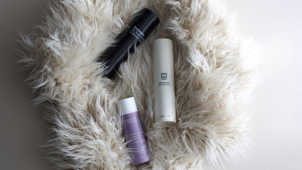 Three beauty products placed on black stone against white background